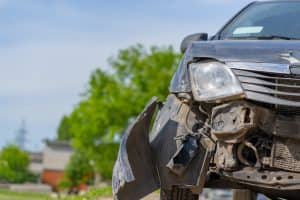 The car after the accident. Broken car on the road. The body of the car is damaged as a result of an accident. High speed head on a car traffic accident. Dents on the car body after a collision on the highway