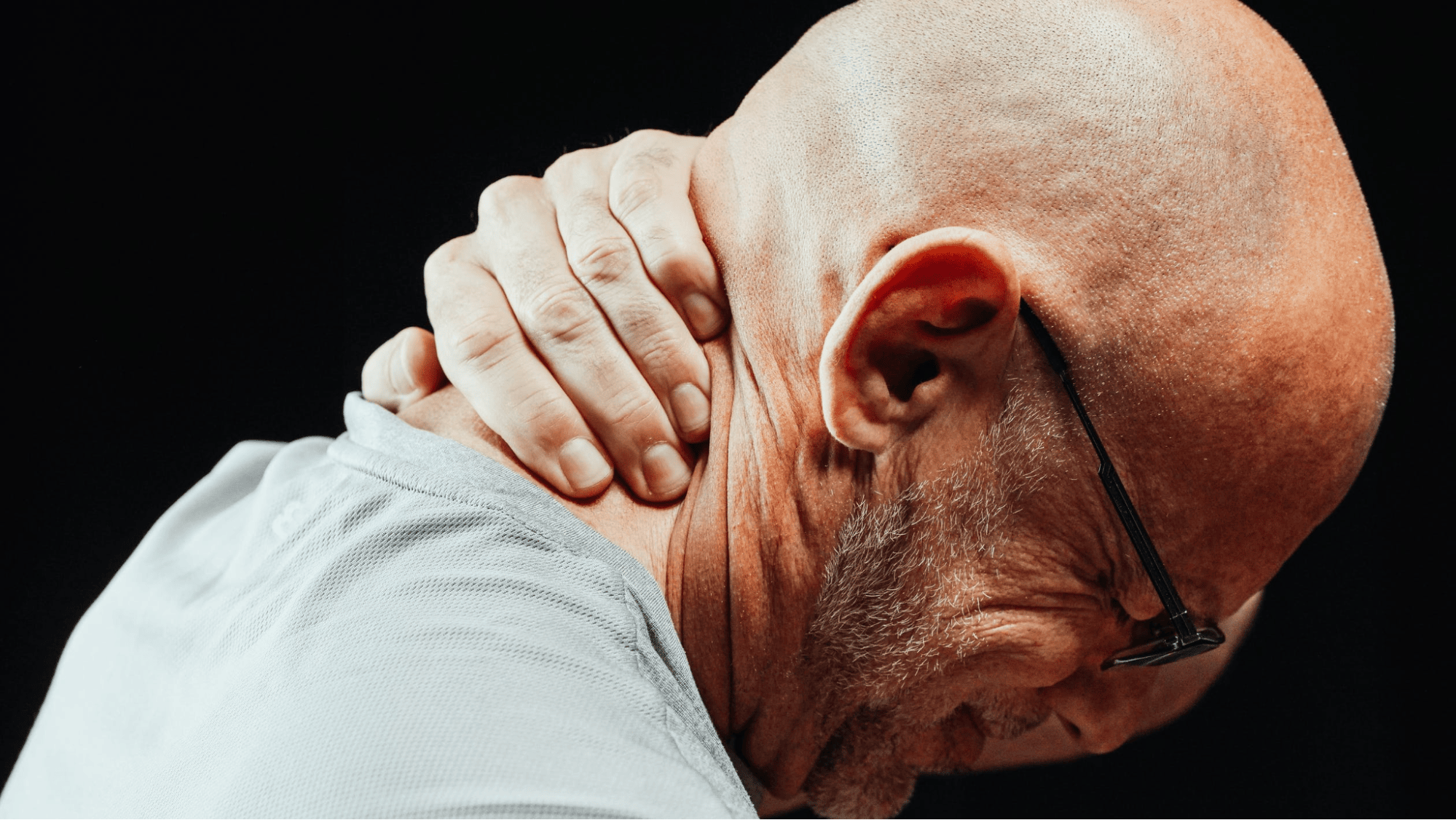 A man rubs his neck after a car accident because of his pain and suffering